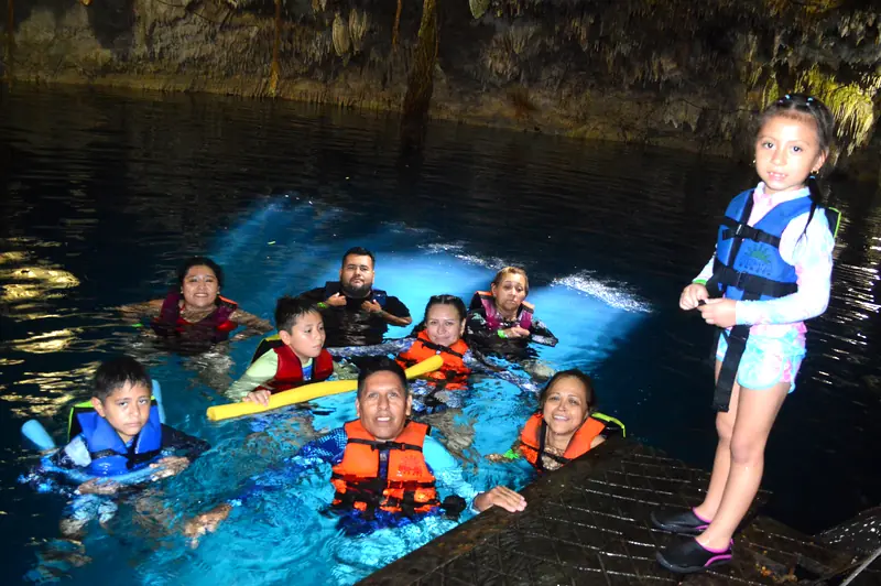 Familia con chalecos salvavidas nadando en el cenote Kin-Ha