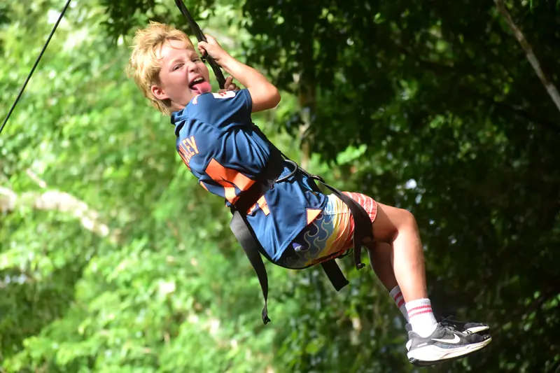 Niño feliz en la tirolesa entre la selva